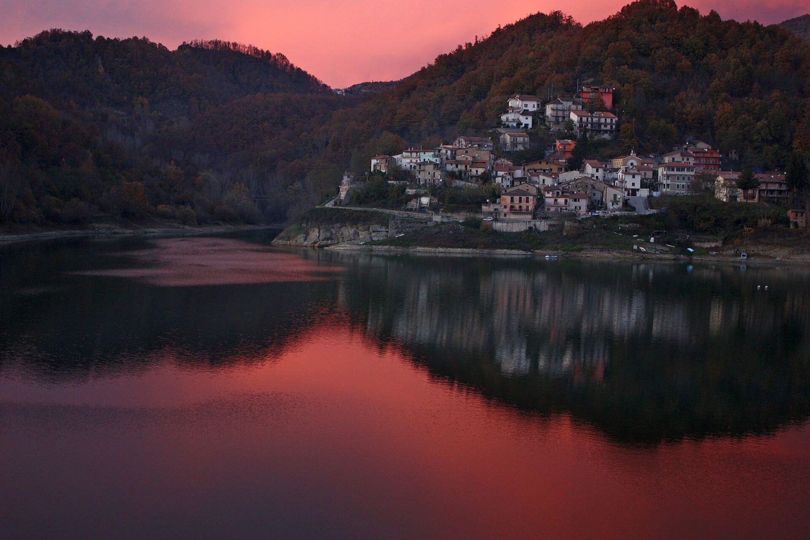 Tramonto rosso sul borgo di Fiumata riflesso nel Lago del Salto